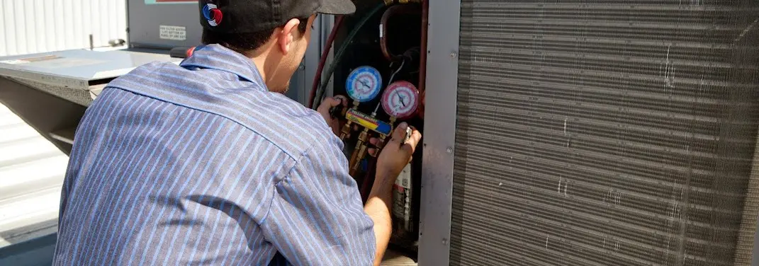 HVAC technician servicing a condenser unit in New Gloucester